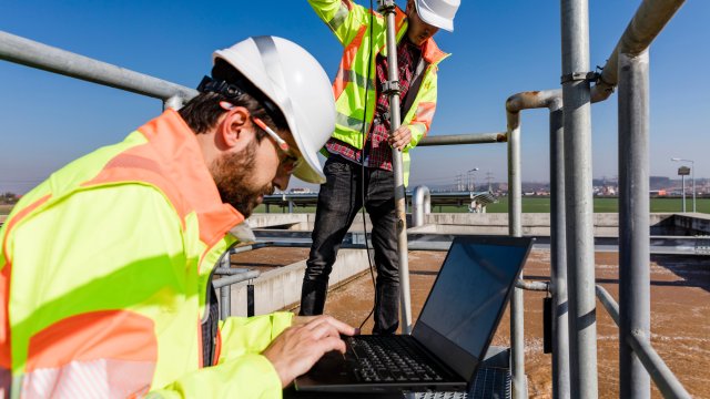 Engineers working on water treatment plant with laptop and measuring sensors