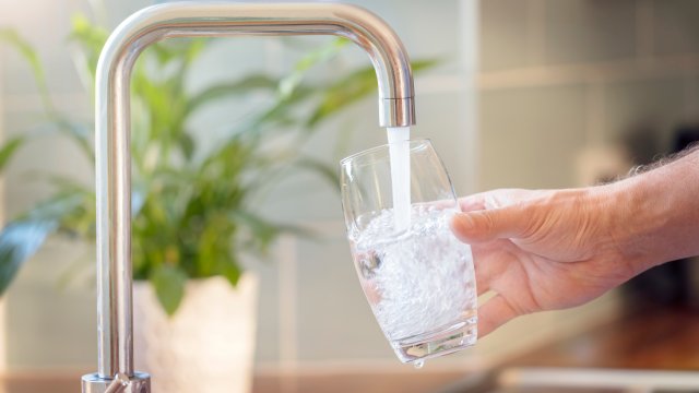 Filling up a glass with clean drinking water from kitchen faucet