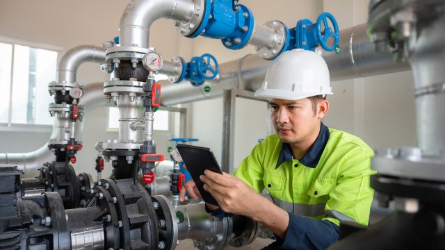 Asian male industrial engineer working Inspection and maintenance of factory water storage pipes or water systems in engineering plants.