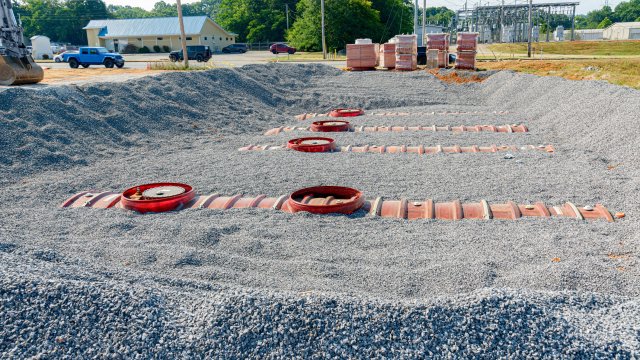 Horizontal close-up shot of four partially buried underground fuel storage tanks at new gas station convenience store construction.