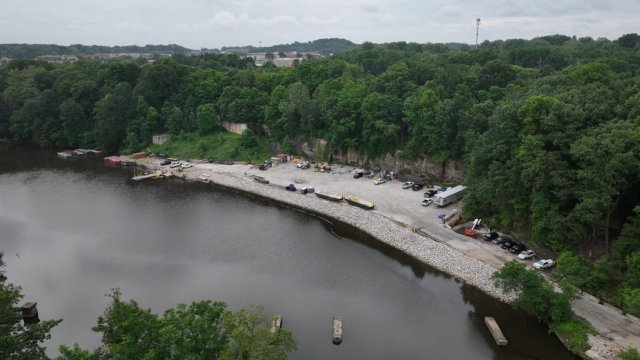 : An aerial image of the former Ohio Edison power plant with equipment, trailers, and barges docked in the Cuyahoga River. 