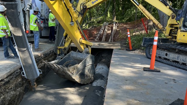 A road with a large cut in it and construction equipment.