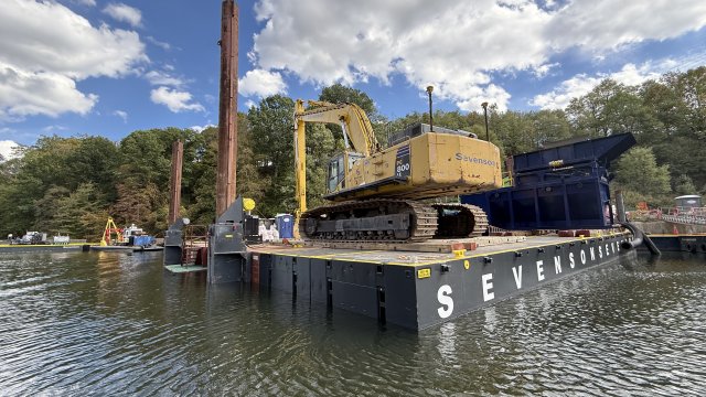 Platform floating on water with construction equipment on top.
