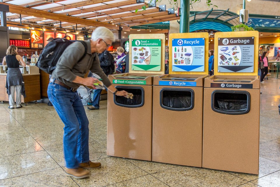 This is a picture of a man throwing a napkin in the composting bin