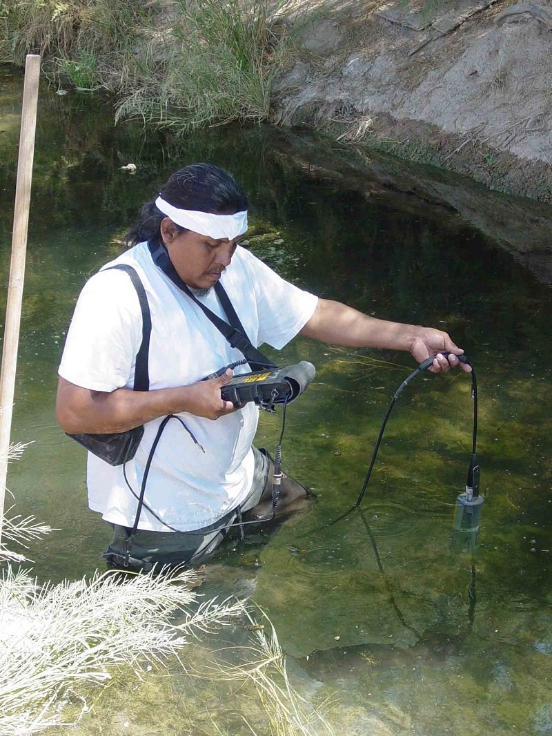 Man standing in river sampling water quality
