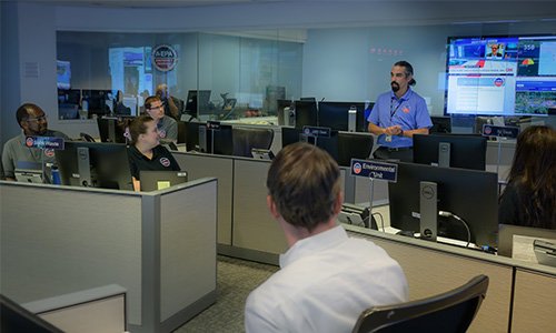 Man addressing a room filled with cubicles