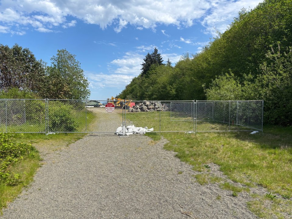 Gravel trail with fence blocking access to construction area beyond.