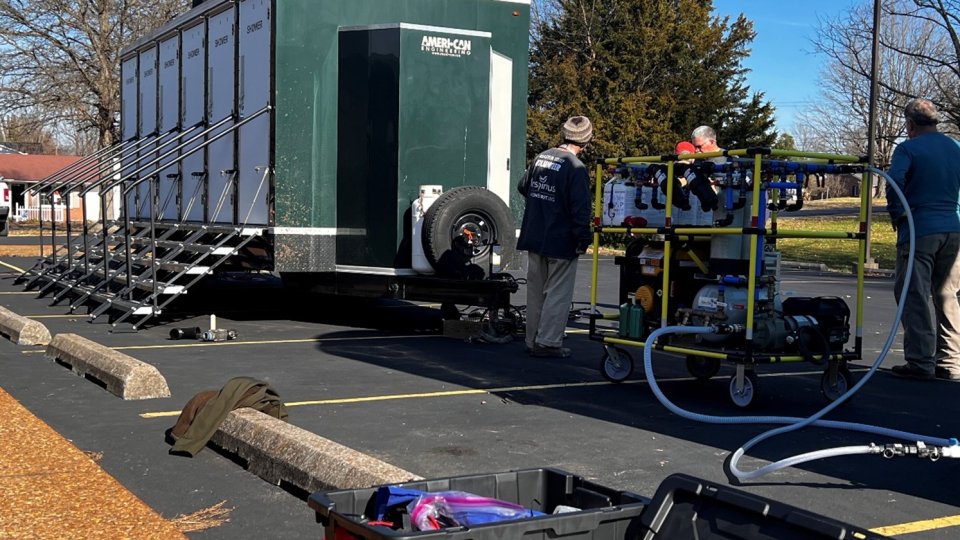 A staging area in a parking lot with a mobile shower trailer and the WOW Cart next to it. 