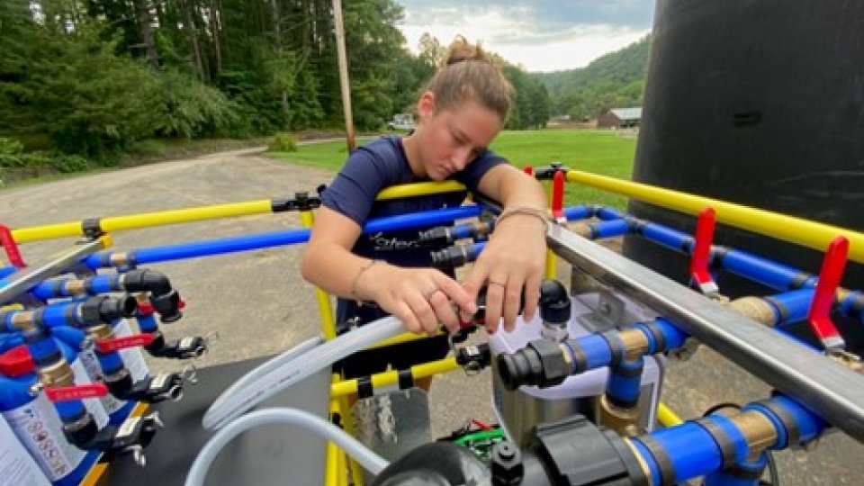 A light-skinned woman connects a hose to the WOW Cart system.