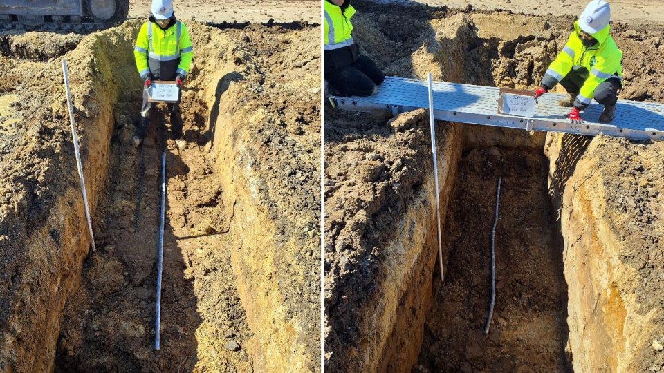 A narrow trench in the ground with a section of pipe laid in it.
