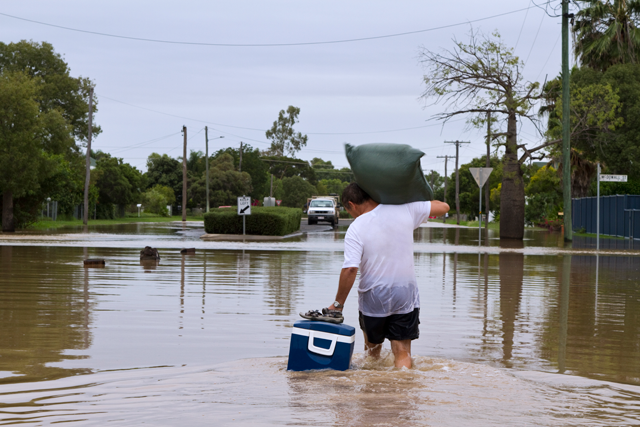 Man wading through flooded street.