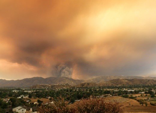 Wildfire spews smoke over the hills near a community.