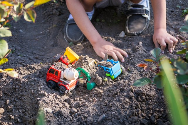 Child plays with toys in the dirt