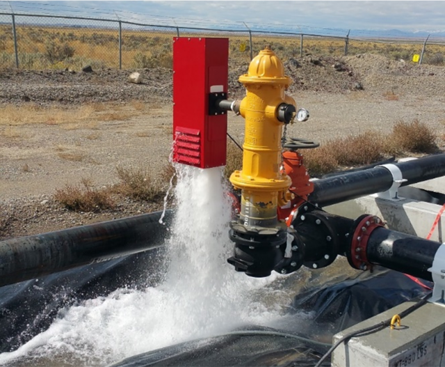 A flushing device attached to a fire hydrant releases water to the ground.