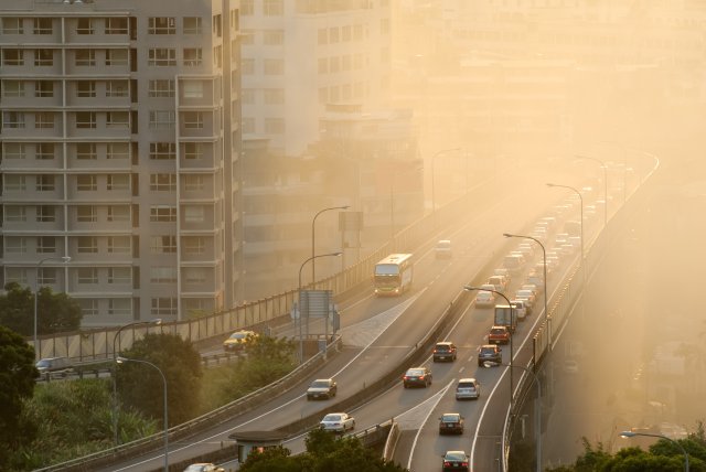 Cars drive down a highway with hazy air around them