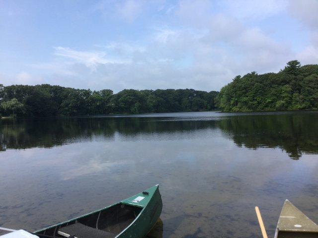 Lake in Rhode Island with tips of two canoes in the foreground