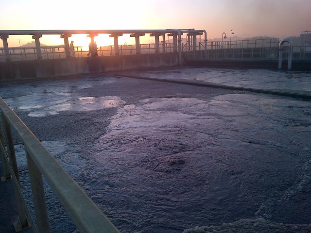 swirling water at sunset with treatment facility walkway in the background