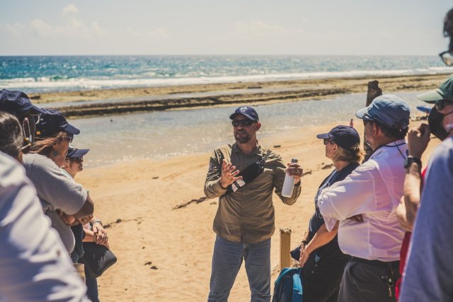 A group gathered around a professor at a beach