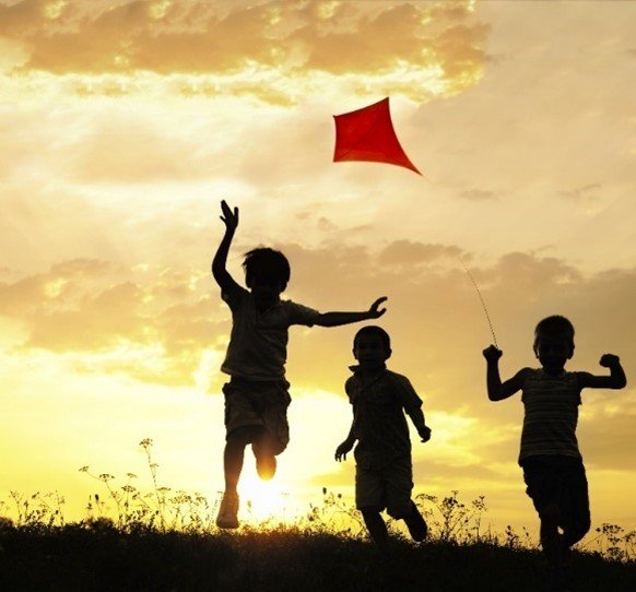 kids chase a kite while the sun sets 