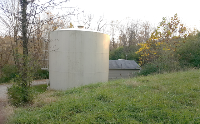 Water storage tank next to a small building and several trees