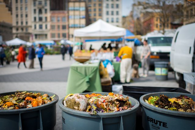 Three trash bins full of food scraps at a farmers market ready to be sent off to be composted