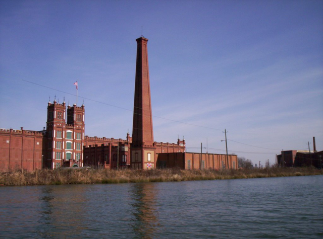 A photo of a brick mill foregrounded by water. 