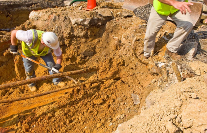 a man digging around some underground pipes