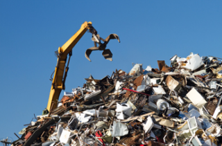 a crane picking up trash at a scrap metal yard