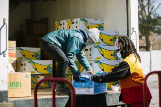 Image of two people unloading a truck of food. 
