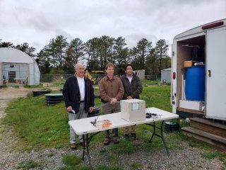 Dr. Qingzhi Zhu, Bud Dunbar, and Brian Feldman stand in front of their successful sensor at the Massachusetts Alternative Septic System Test Center.