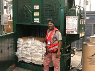 Image of a man standing next to trash compactor. 