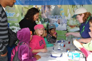 Dr. Gwinn leads youngsters in a hands-on science experiment at a science festival.