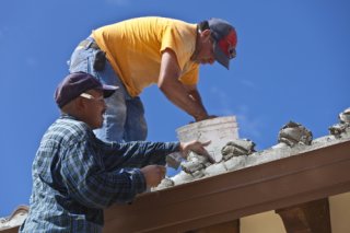 Two roofers working on a exterior tile roof on a sunny day.