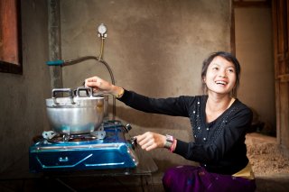 image of a woman using a clean burning cookstove indoors
