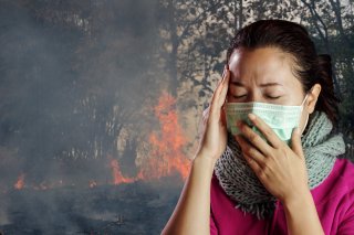 Person in mask in front of wildfire