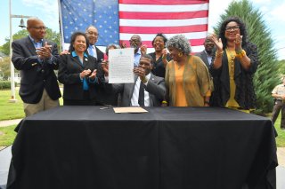 Administrator Regan holding up signed paper creating the Office of Environmental Justice and External Civil Rights