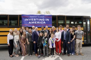 Children and Administrator Regan in front of an electric school bus