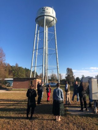 People looking up at a water tower.