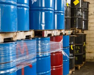 This is a picture of blue, red, and black drums stacked neatly in a row on pallets