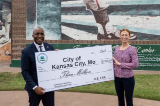 two people holding up a big check award for brownfields in kansas city, mo