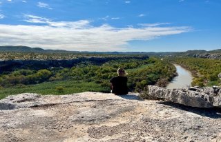 Olivares-McLaughlin seated on a cliff overlooking the Rio Bravo