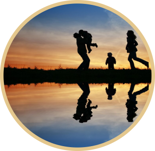 A photo of four silhouettes at sunset. A person is picking up a child.