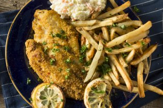 Plate of fried catfish and french fries with lemon slices.