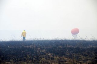 Researcher in a yellow jacket approaches a thick balloon used for the burn study