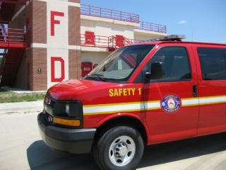 A red vehicle in front of a fire department building.