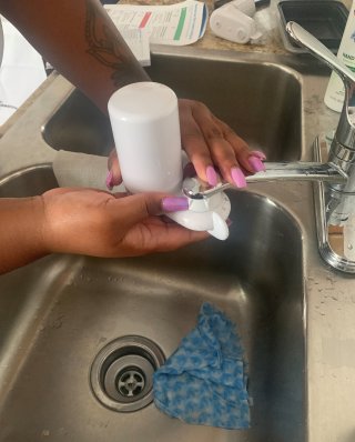 A person's hands installing a faucet water filter over their kitchen sink.