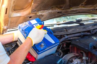 man taking a lead acid battery out of a car