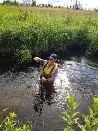 A biologist installs equipment in a stream