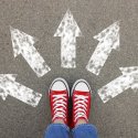 Looking down at red shows. Arrows drawn on asphalt point in different directions